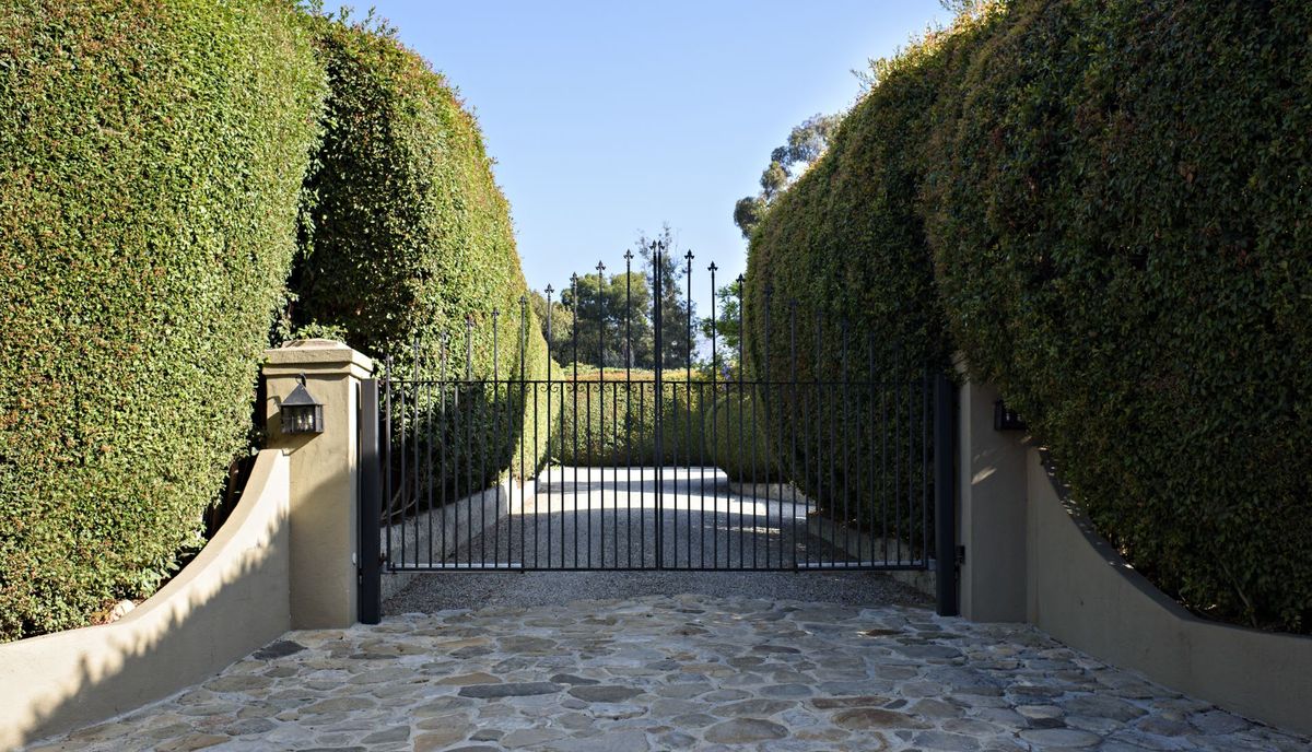 An estate gate between tall hedges
